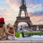 A mother and her daughter looking at the sunset view of the Eiffel Tower